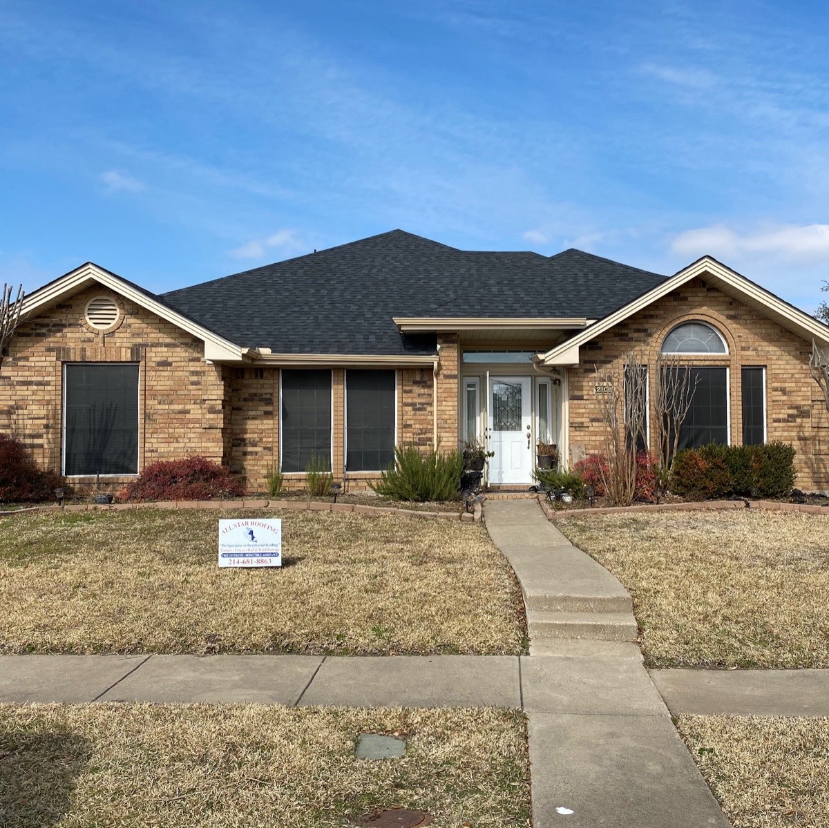 Completed asphalt shingle roof replacement on a brick home in Garland, TX with All Star Roofing yard sign