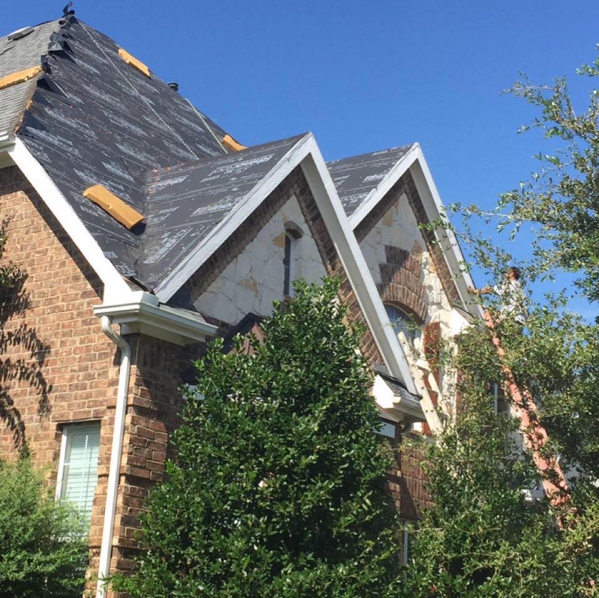 All Star Roofing crew installing synthetic underlayment on a two-story brick home